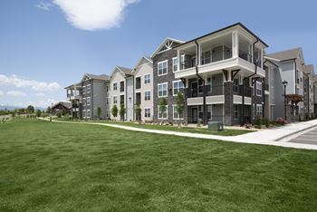 an exterior view of an apartment building on a green lawn  at Watermark at Harvest Junction, Colorado